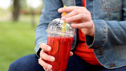 Girl in a denim jacket with lemonade in her hands, takeaway drink. Refreshing drink against the...