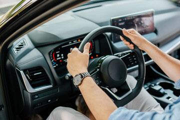 Close-up of a man's hands holding the steering wheel of a car. Concept of traveling and car trips.