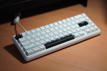 A wired 65% mechanical keyboard with a monochrome (black and white) theme on a wooden table.