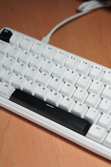 A wired 65% mechanical keyboard with a monochrome (black and white) theme on a wooden table.