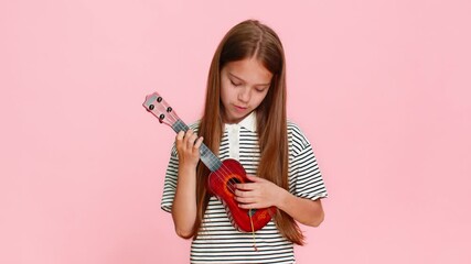 Young child girl joyfully plays a toy ukulele, pretending to perform on stage, smiling with enthusiasm musical imagination while posing on a vibrant background. School kid isolated on pink background - Powered by Adobe