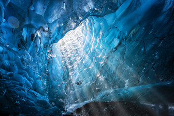 Blue glacial ice with hole through to the sky with sun rays, from an ice cave in the glacier....