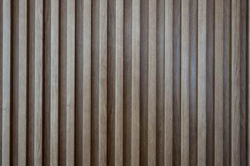 A close up view of a vertical slatted wall or partition, showcasing a repeating pattern of narrow,...