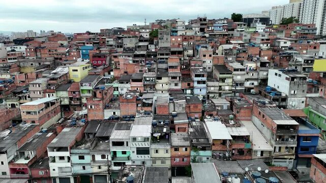 Drone footage reveals a tightly packed favela in Osasco, S&atilde;o Paulo, Brazil, highlighting informal urban housing with rooftop water tanks and dense residential sprawl. 