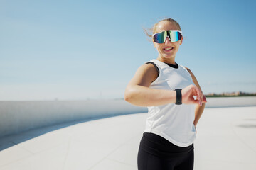 Smiling Athlete Checks Fitness Tracker While Enjoying Sunny Day by the Waterfront During Early...