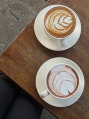 two cups of latte art on the wood table