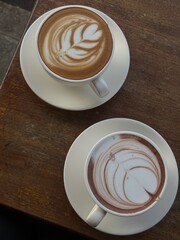 two cups of latte art on the wood table