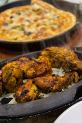 Delicious sizzling chicken on a hot plate with pizza.