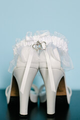 Elegant white heels with garter accessorized for a wedding celebration set against a soft blue background
