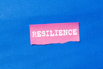 Resilience message written on ripped torn pink paper on blue background. Conceptual resilience...