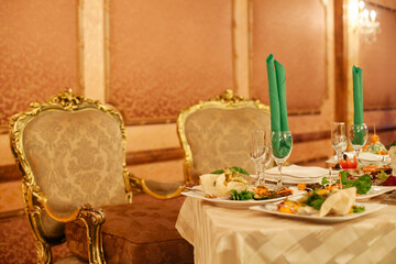 Elegant dining setup with gourmet dishes and ornate chairs in a luxurious restaurant setting during evening hours