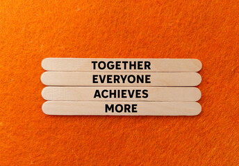 Together everyone achieves more message written on wooden sticks on orange background. Conceptual together everyone achieves more symbol. Copy space.