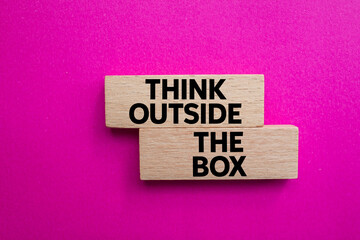 Think outside the box message written on wooden blocks on pink background. Conceptual think outside the box symbol. Copy space.