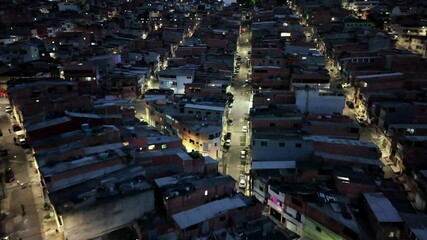 Aerial top-down shot of urban streets in a São Paulo favela at night, with glowing lights, narrow alleys, and compact housing in Osasco, Brazil. - Powered by Adobe