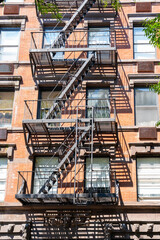 Obraz premium An old red brick apartment building with fire escape stairs. New York City, USA