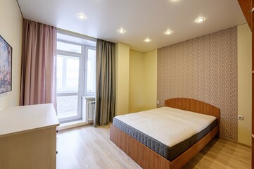 bright bedroom featuring a wooden bed, patterned wallpaper, pink and grey curtains, and light wooden floors