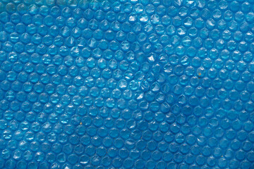 Blue bubble wrap texture with a smooth, glossy surface. The bubbles are evenly spaced, creating a uniform pattern. Ideal for backgrounds and abstract designs.