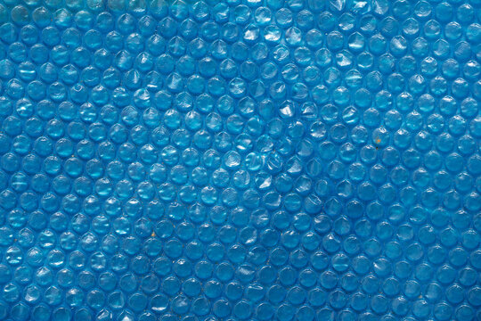 Blue bubble wrap texture with a smooth, glossy surface. The bubbles are evenly spaced, creating a uniform pattern. Ideal for backgrounds and abstract designs.