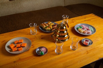 Oriental sweets baklava and lukum on a wooden table next to a Turkish teapot and cups