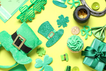 Leprechaun hat with gift box, cupcake and decor for St. Patrick's Day on yellow background