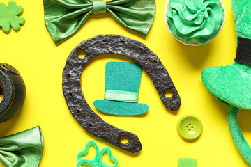 Leprechaun hat with horseshoe, bow ties and cupcake on yellow background. St. Patrick's Day...