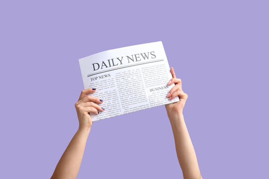 Female hands with newspaper on lilac background