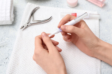 Female hands with cuticle oil pens, towel and cutter on blue grunge background
