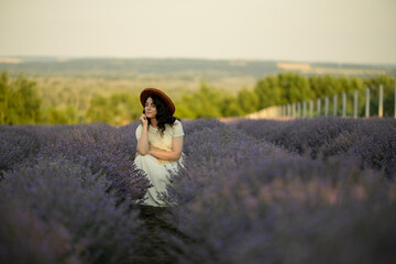 A young brunette walks in wheat fields at sunset in summer. Growing organic wheat and barley.