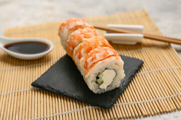 Board with tasty sushi rolls on bamboo mat, closeup