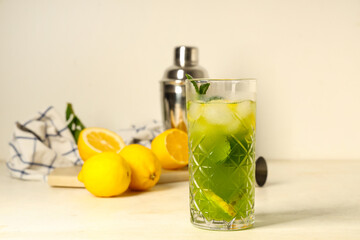 Glass of lemonade with lemons and mint on white background
