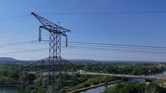 vue a&eacute;rienne autour d'un pyl&ocirc;ne &eacute;lectrique &agrave; haute tension, &agrave; l'arri&egrave;re plan on voit une autoroute et une zone industrielle