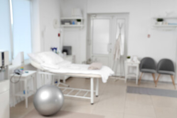 Blurred view of hospital ward with bed, door and clothes rack