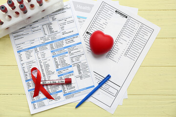 HIV blood test tubes, laboratory report form, heart and red ribbon on yellow wooden background