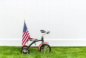Fototapete vintage tricycle with American flag on green grass with horizontal white background and room for copy © zenmaster8