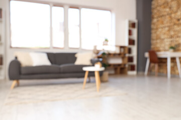 Blurred view of grey sofa and bookshelf with books in living room