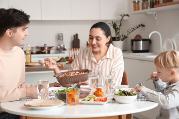 Young woman putting Fajita on her husband's plate at family dinner in kitchen