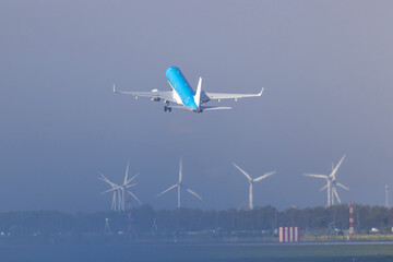 KLM airplane taking off over wind turbines at Amsterdam Schiphol Airport