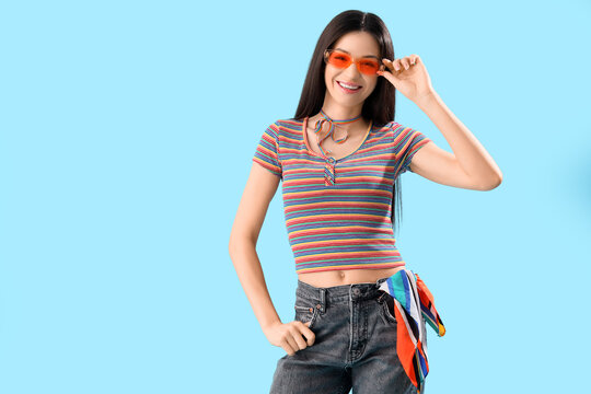 Fototapeta Beautiful young woman in rainbow t-shirt on blue background. LGBT concept