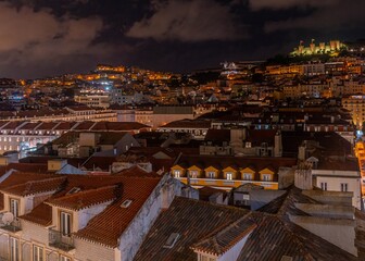 The night panorama of rooftops in Alfama district with the illuminated castle of São Jorge. 