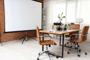Interior of conference hall with projector screen, shelf unit and table