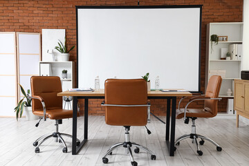 Interior of conference hall with projector screen, shelf units and table