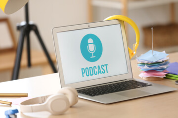 Laptop with headphones on table in podcaster's studio, closeup