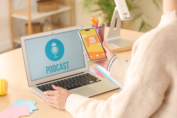 Female podcaster using mobile phone at table in studio, closeup