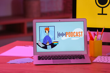 Laptop with podcast on podcaster's table in dark studio, closeup