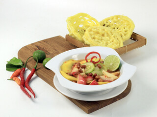 Asinan buah Bogor - fresh pickled fruit with red sauce and a sprinkling of fried peanuts in a white bowl on a white background