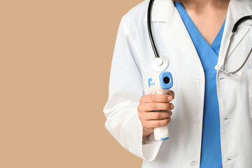 Female cardiologist with stethoscope and infrared thermometer on beige background, closeup
