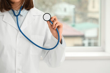 Female cardiologist with stethoscope in clinic, closeup