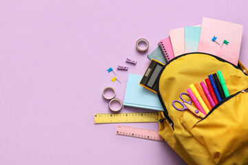 Yellow school backpack with different stationery supplies on lilac background