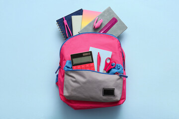 Stylish school backpack with different stationery supplies on blue background