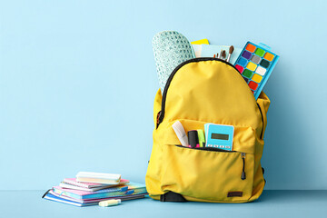 School backpack with different stationery on blue background
